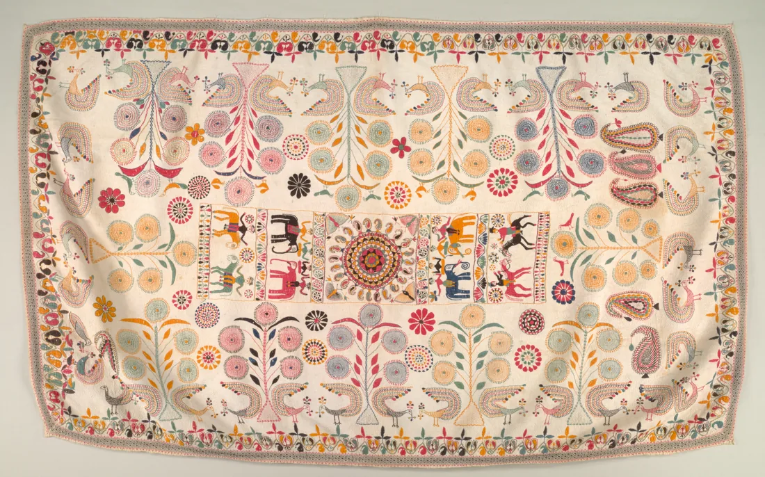 A white Bengal kantha embroidered with small coloured figures and curling forms.